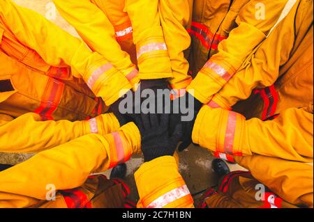 Firefighter putting hands up for fire fighting, Cheerful people giving strength motivation. Teamwork concept Stock Photo