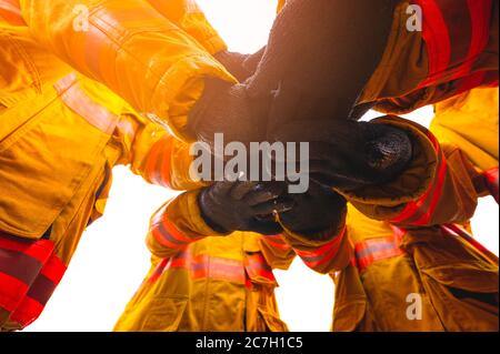 Firefighter putting hands up for fire fighting, Cheerful people giving strength motivation. Teamwork concept Stock Photo