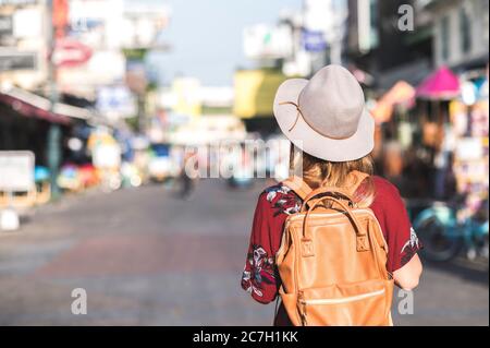 Travel Thailand concept. Young woman with hat traveling in walking street Khaosan road  in Bangkok, Thailand