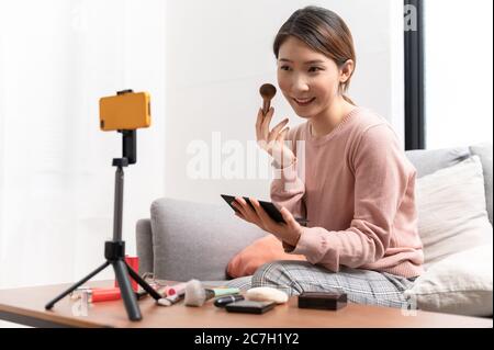 Asian woman blogger live steam video of makeup cosmetic at home online influencer on social media concept Stock Photo