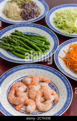 Prawns, green asparagus, carrots, iceberg lettuce and alfalfa on a wooden table Stock Photo