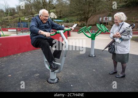 Elderly couple in their eighties at an exercise park trying out the apparatus together, Kingsbridge, Devon, England, United Kingdom Stock Photo