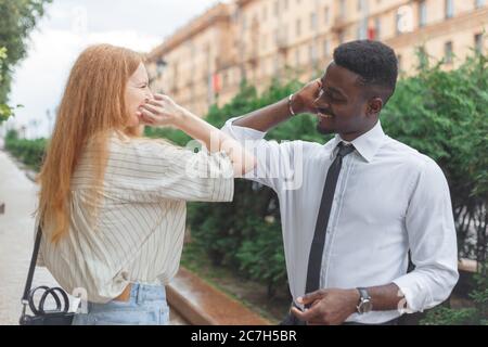 Elbow bump greeting to avoid the spread of coronavirus. Black man and caucasian woman use elbows instead palms for greeting