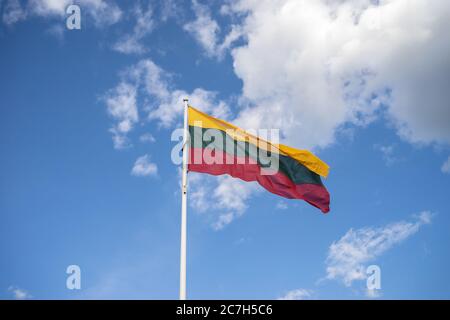 Low angle view of the flag of Lithuania on a metallic pipe under a blue sky and sunlight Stock Photo