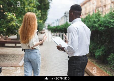 Obsessive black man in business attire interview on the street bothering passersby with questions Stock Photo