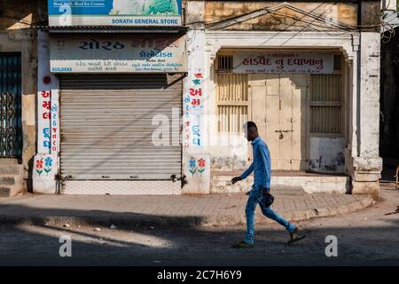Junagadh, Gujarat, India - December 2018: A man walks past the shuttered doors of a closed market in the old city. Stock Photo