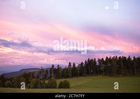 Picturesque sunset cloudscape over the Jura mountains. Beautiful evening sky landscape over the meadows and forest. Stock Photo