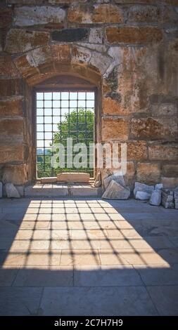 Vertical shot of a window with metal bars casting a shadow at daytime Stock Photo