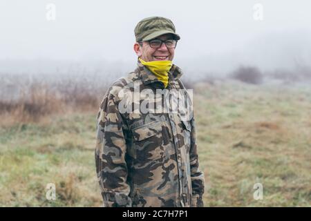 portrait of a senior soldier standing at the field and smiling Stock Photo