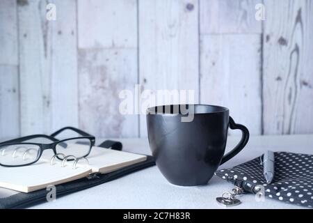 black mug mockup, modern workspace with notepad and eyeglass on table. Stock Photo