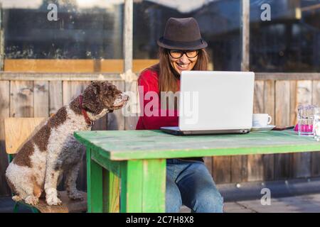young woman working on laptop in company of her dog Stock Photo
