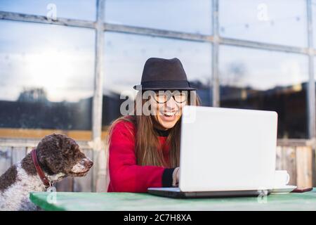 young woman working on laptop in company of her dog Stock Photo
