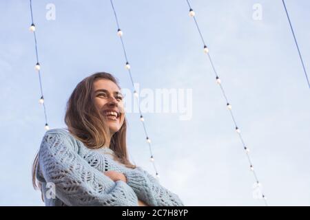 happy young woman standing under festival lights outdoors Stock Photo