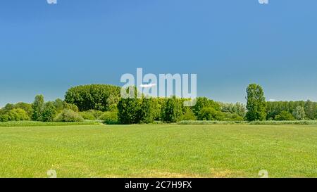 Sunny mown meadows with trees under a clear blue sky in Kalkense ...