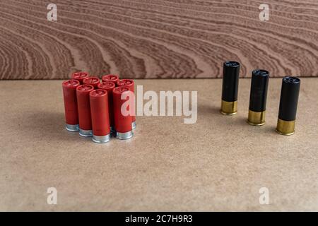 Selective focus shot of red shotgun shells near three black shotgun shells on a brown surface Stock Photo