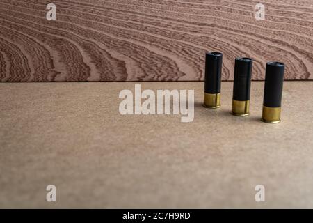 Selective focus shot of three black shotgun shells on a brown surface Stock Photo