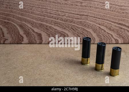 Closeup shot of three black shotgun ammo on a brown surface Stock Photo