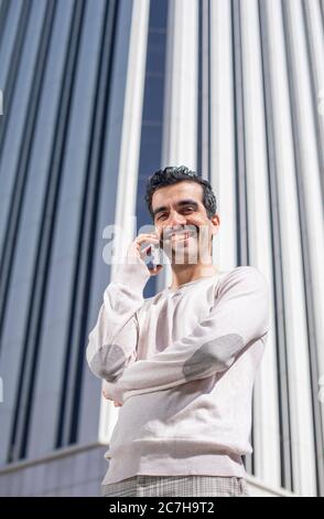 young smiling executive man next to offices talking on the phone Stock Photo