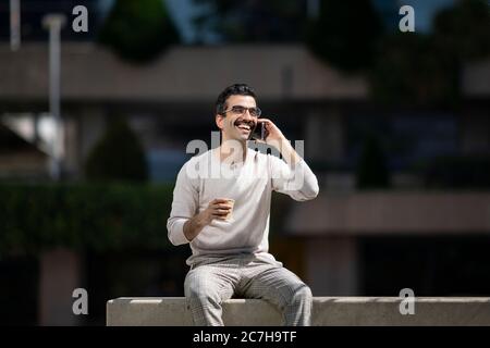 young smiling executive man next to offices talking on the phone Stock Photo