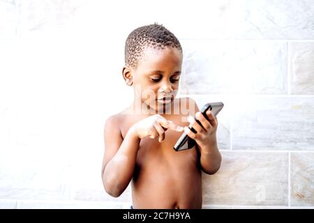 Nice african boy has fun using a mobile phone. Stock Photo