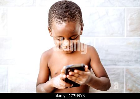 Nice african boy has fun using a mobile phone. Stock Photo