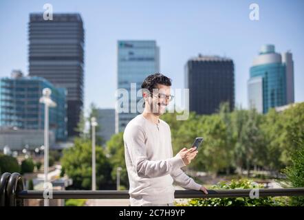 young smiling executive worker with mobile phone with an office skyline in the background Stock Photo