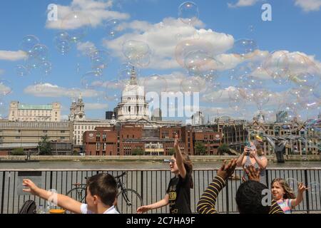 London, UK. 17th July, 2020. A soap bubble making artist entertains children and adults in front of a beautiful St Paul's Cathedral backdrop. Lovely sunshine and warm temperatures are set to continue into the weekend. Credit: Imageplotter/Alamy Live News Stock Photo