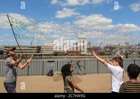 London, UK. 17th July, 2020. A soap bubble making artist entertains children and adults in front of a beautiful St Paul's Cathedral backdrop. Lovely sunshine and warm temperatures are set to continue into the weekend. Credit: Imageplotter/Alamy Live News Stock Photo