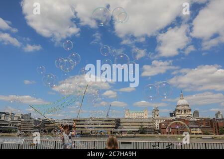 London, UK. 17th July, 2020. A soap bubble making artist entertains children and adults in front of a beautiful St Paul's Cathedral backdrop. Lovely sunshine and warm temperatures are set to continue into the weekend. Credit: Imageplotter/Alamy Live News Stock Photo