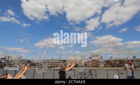 London, UK. 17th July, 2020. A soap bubble making artist entertains children and adults in front of a beautiful St Paul's Cathedral backdrop. Lovely sunshine and warm temperatures are set to continue into the weekend. Credit: Imageplotter/Alamy Live News Stock Photo