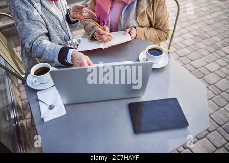 Women with pencil and red notebook doing home work at the terrace cafe Stock Photo