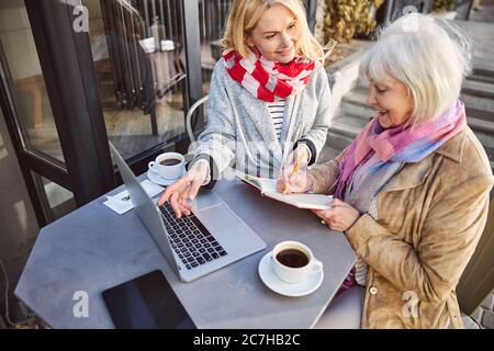 Stylish two ladies sitting in the cafe terrace with computer Stock Photo