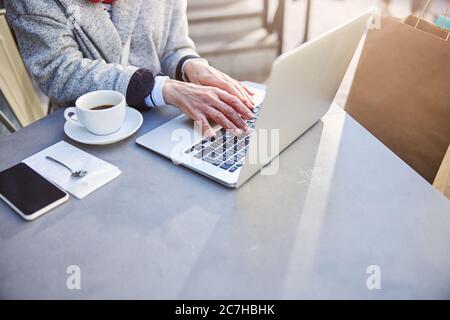 Mature lady working on notebook with cup of coffee Stock Photo