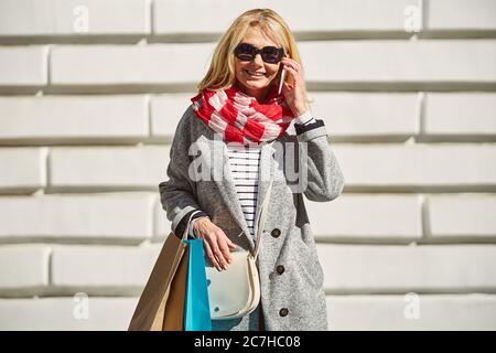 Happy Caucasian smiling woman with shopping bags standing on the street Stock Photo
