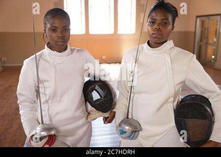 Portrait of two female fencers holding fencing foil and mask Stock Photo