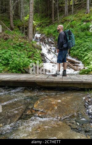 Europe, Austria, Tyrol, Ötztal Alps, Ötztal, hikers on a small wooden bridge in the mountain forest above Sölden Stock Photo