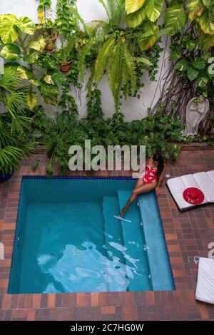 America, Caribbean, Greater Antilles, Dominican Republic, Santo Domingo, Zona Colonial, Hotel Colonial 154 H Boutique, woman sitting by the pool Stock Photo