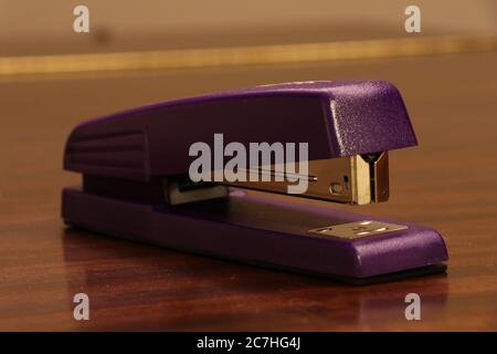 Closeup shot of a purple stapler on a wooden surface Stock Photo