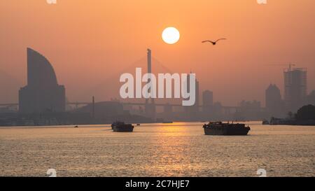 Sun rising above Huangpu River. Colorful dusk with Yangpu Bridge in the background. Stock Photo