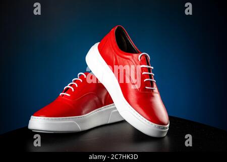 mens red leather shoes with white soles on blue background Stock Photo