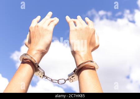 Close up two hands in handcuffs and put your hands up for freedom meaning with blue sky at background. freedom concept. Stock Photo