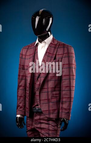 Luxurious men's burgundy three-piece suit, white shirt on dummy or mannequin on blue background Stock Photo