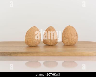 Three walnuts on a wooden cutting board Stock Photo