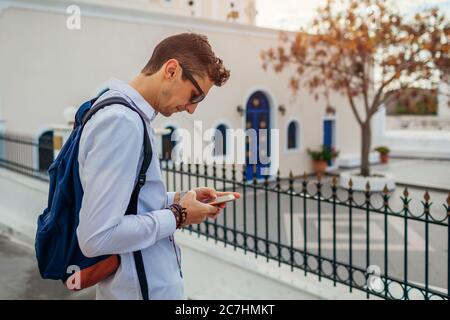 Santorini traveler using smartphone on street. Man with backpack checking navigator. Tourism, traveling, vacation Stock Photo