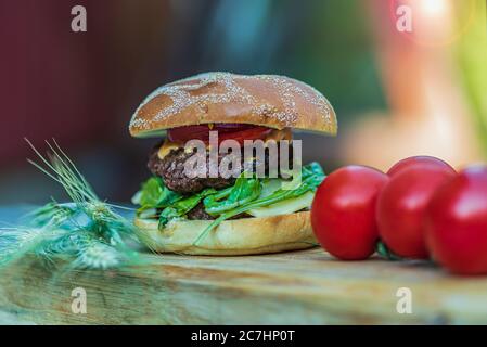 Finished Grilled sirloin burger with salad and tomatoes one summer evening in the Swedish countryside Stock Photo