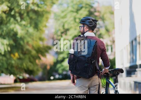 Male commuter or messenger with a bike in urban background. Safe cycling in the city, going to work by bicycle, delivery man image Stock Photo