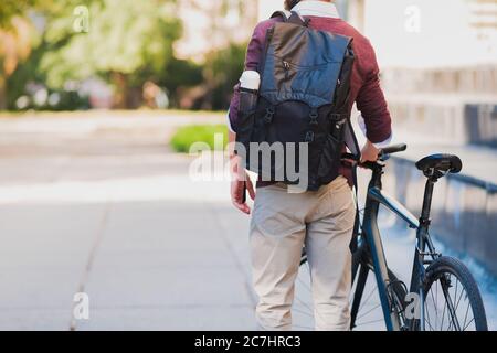 Male commuter or messenger with a bike in urban background. Safe cycling in the city, going to work by bicycle, delivery man image Stock Photo