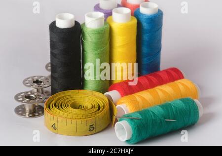 Sewing tools collection. thread sewing needle, measuring tape, bobbins, in a white background. Stock Photo