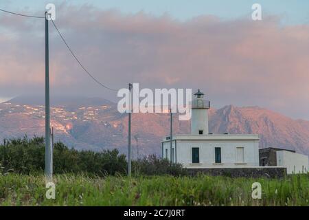 Sicily - Sunny impressions of the Aeolian Islands, also known as Aeolian Islands or Isole Eolie: Lipari, Stromboli, Salina, Vulcano, Panarea, Filicudi and Alicudi. Lighthouse on the island of Salina in Lingua at sunset. In the background the island of Lipari. Stock Photo