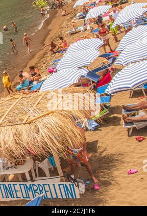 Sicily - Sunny impressions of the Aeolian Islands, also known as Aeolian Islands or Isole Eolie: Lipari, Stromboli, Salina, Vulcano, Panarea, Filicudi and Alicudi. Beach life on Panarea: parasol rental on the Zimmari sandy beach. Stock Photo